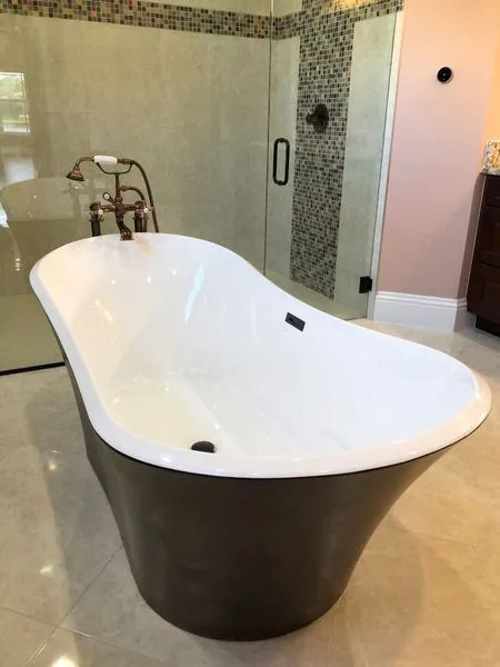 Freestanding soaker tub beside a glass-mosaic shower